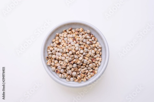 Fototapeta Uncooked raw Sorghum (also known as sorgo) in a white bowl, isolated on white background