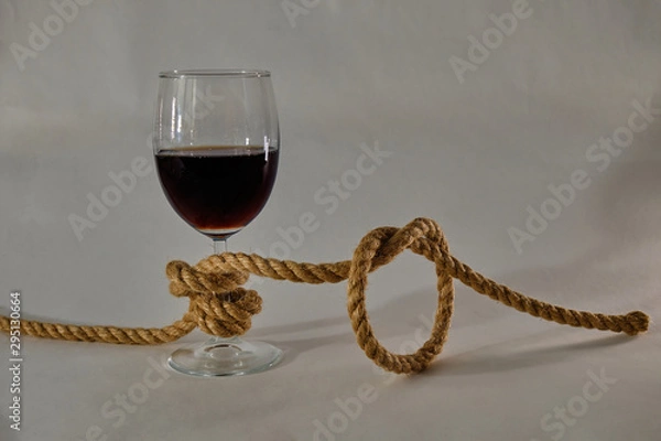 Fototapeta A glass of wine tied in a knot with a jute rope. Alcohol addiction