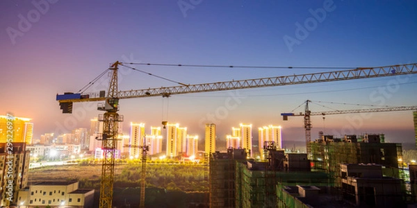 Fototapeta Tower cranes build residential buildings at nigh