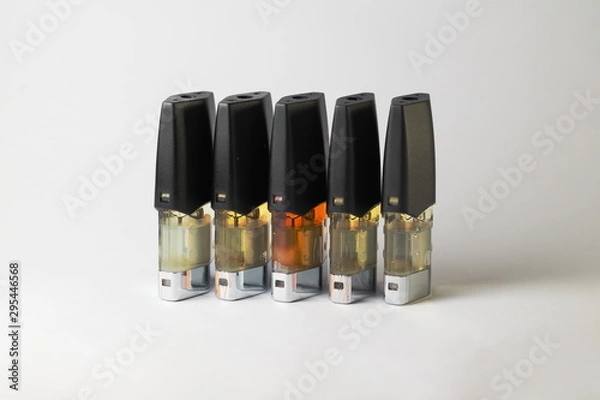 Fototapeta e-juice vape refill pods with liquids of different shades of orange yellow, white background isolated close up