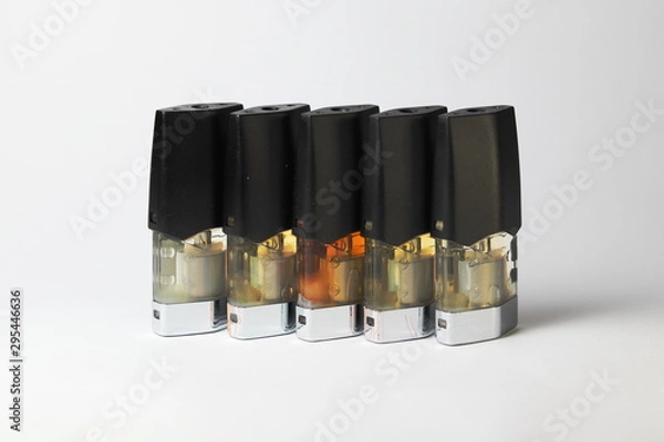 Fototapeta e-juice vape refill pods with liquids of different shades of orange yellow, white background isolated close up