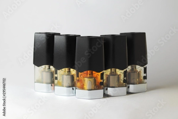 Fototapeta e-juice vape refill pods with liquids of different shades of orange yellow, white background isolated close up