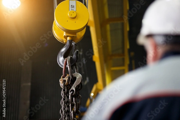 Obraz Yellow overhead-traveling crane with hard hat worker operator