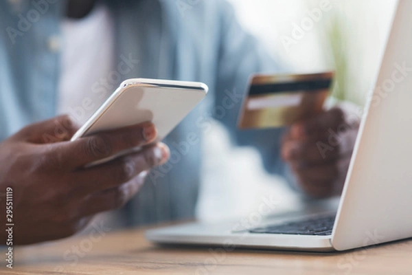 Fototapeta Unrecognizable black man using smartphone and credit card, shopping online