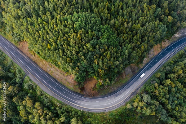 Fototapeta Top down aerial view of mountain road curve among green forest trees. Small cargo truck on the highway. P-258 road on the shore of Baikal Lake near Baikalsk, Buryatia, Russia