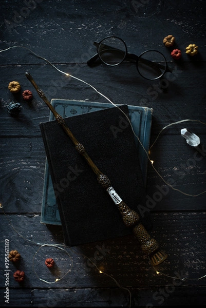 Obraz magic wand and spell books on desk with glasses and other witch items, wizards desk, halloween theme, vintage books