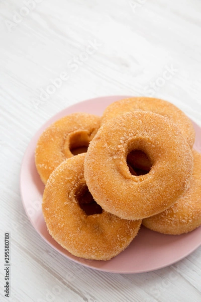 Fototapeta Homemade autumn apple donuts on a pink plate on a white wooden background, low angle view. Copy space.