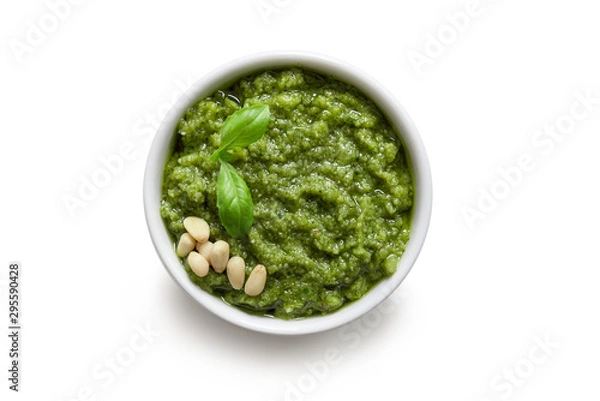 Fototapeta Bowl of green italian homemade sauce pesto made of ground basil, garlic, pine seeds, olives and pecorino sardo cheese. Top view isolated on white background