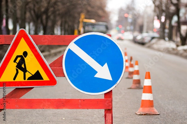Fototapeta Road under construction traffic sign with a roadsign diversion on the right in the city.