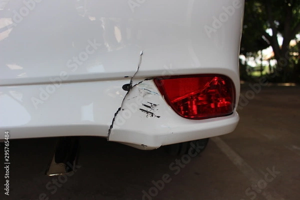 Fototapeta The rear bumper of a white car has cracks due to an accident on the road