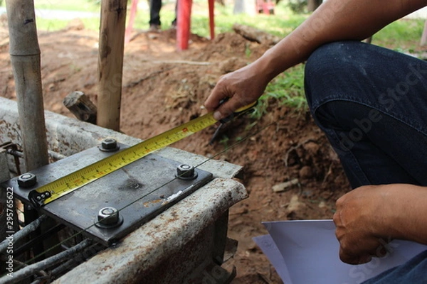 Fototapeta The technicians are using tape measure to measure the size of the steel plate used in the construction of the house
