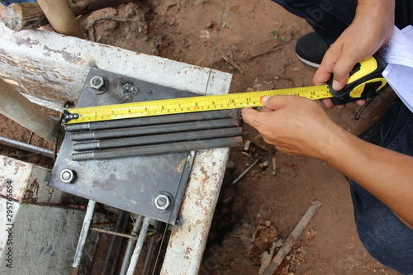 Fototapeta Technicians use tape measure to measure the size of the steel sheet used in construction