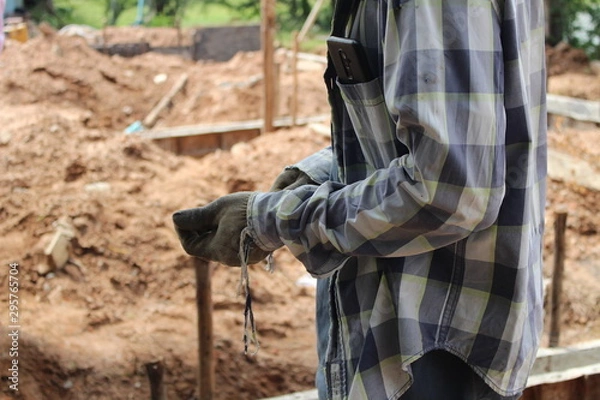 Fototapeta Construction workers are on the construction site and have phones in their pockets