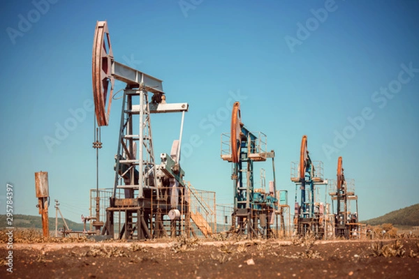 Fototapeta Oil pump jack rocking with pipeline in the background. Rocking machines for power generation. Extraction of oil