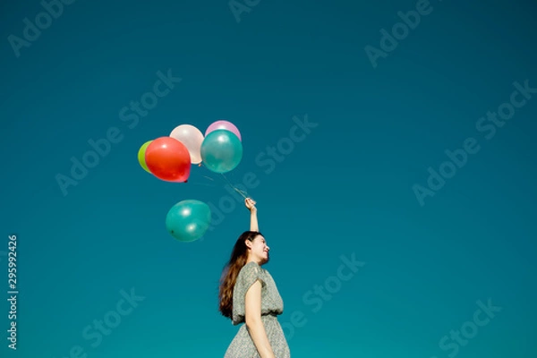 Fototapeta Happy asian woman playing colorful balloons on blue sky background. Freedom concept