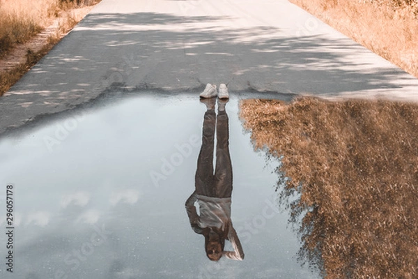 Fototapeta Reflection of a person standing near a puddle. Style is a reflection of your attitude and your personality. The concept of loneliness.