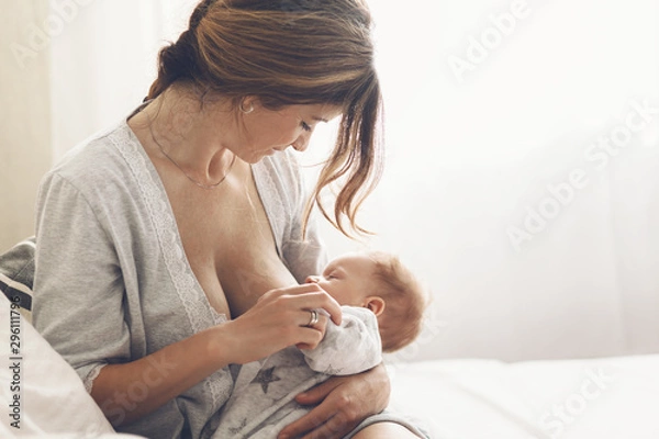 Obraz Kochająca mama karmi piersią swojego noworodka w domu