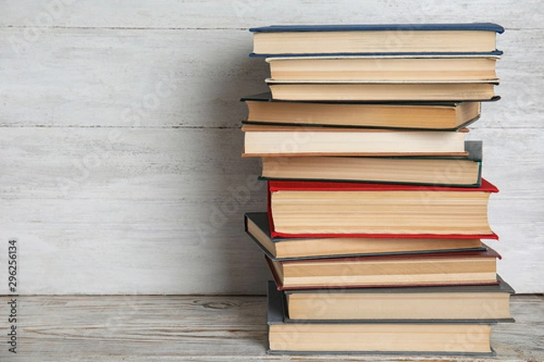 Fototapeta Stack of hardcover books on wooden table against white background. Space for text