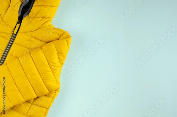 Obraz Yellow kids winter jacket composition on blue background.