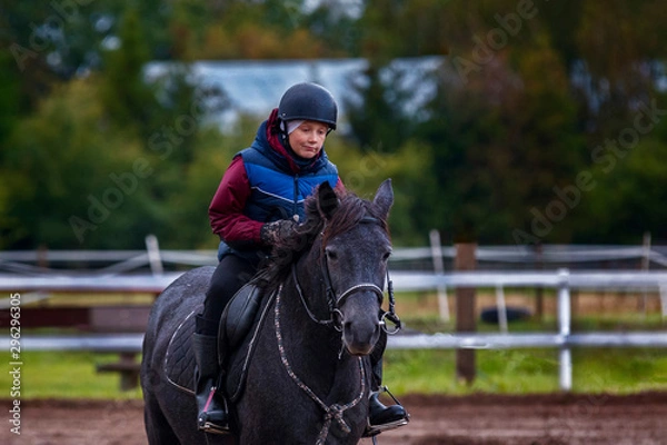 Obraz A little boy riding a horse safely