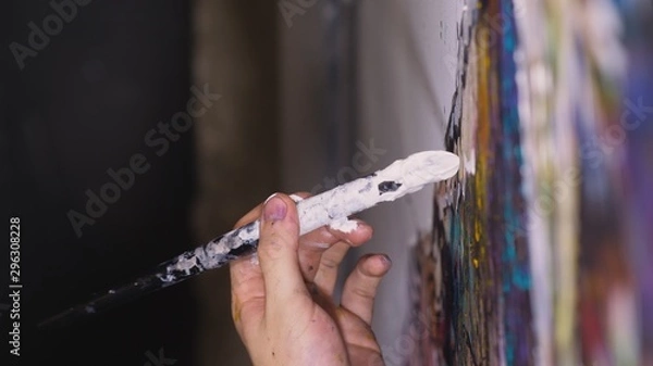 Fototapeta Artist designer draws an eagle on the wall. Craftsman decorator paints a picture with acrylic oil color brush. Close-up dark magic cinematic look.