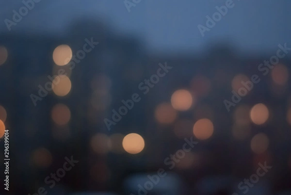 Fototapeta Blurred background of evening cityscape with luminous windows