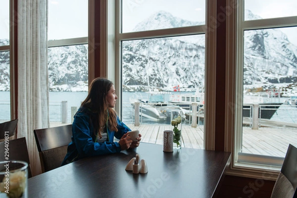 Fototapeta Norway. Girl sitting in cafe with Cup of coffee. Looks thoughtfully out window