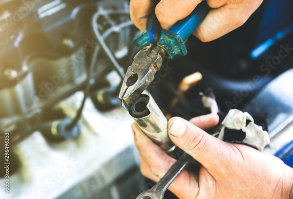Fototapeta Man holding spark plug in old car engine. Inner details of machine. Repairing of vehicle.