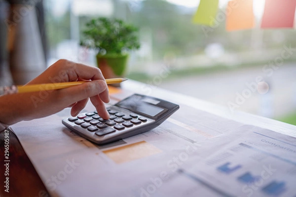 Obraz Close up of businesswoman or accountant working on calculator to calculate business data, and accountancy document. Business financial and accounting concept.