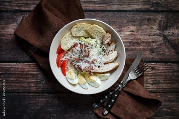Fototapeta Caesar salad with grilled chicken with dressing on rustic wooden table