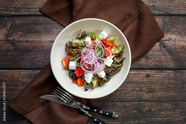 Fototapeta Greek salad with red onions, feta cheese, cherry tomatoes and olives on dark wooden table