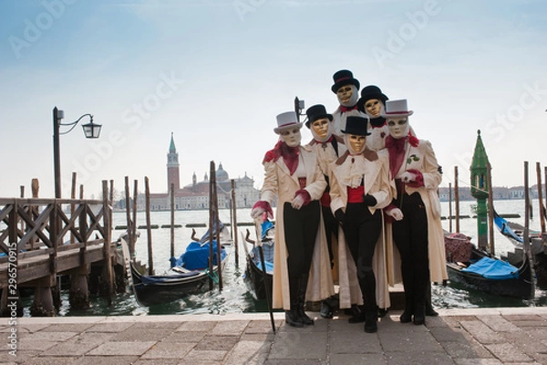 Fototapeta A group of people in masks for the Venice carnival in San Marco piazza, in the background the island of San Giorgio Maggiore. Italy