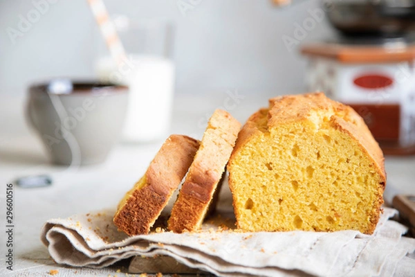Fototapeta Pumpkin cake on beige dish cloth with cup of tea, glass of milk and tree branch on background. Autumn dessert.