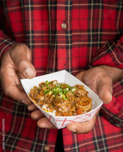 Fototapeta Holding shrimp creole close with two hands vertical