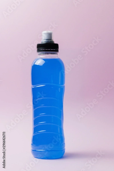 Fototapeta Bottle with blue clear liquid, sports energy drink on pink background. Selective focus