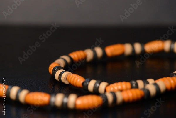 Fototapeta Fragment of a wooden beads necklace on a dark background close up