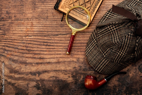 Fototapeta Literacka fikcja, zbadanie konceptualnego pomysłu na przestępczość i tajemnicę z czapką detektywa Sherlocka Holmesa, fajką, szkłem powiększającym retro i starą książką odizolowaną na drewnianym blacie z miejscem na kopię
