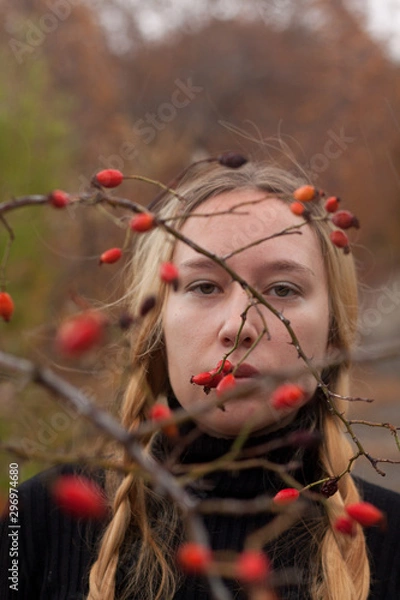 Obraz autumn portrait of pensive young woman behind the branches of a rosehip bush
