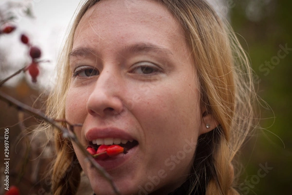 Obraz autumn portrait of pensive young woman behind the branches of a rosehip bush