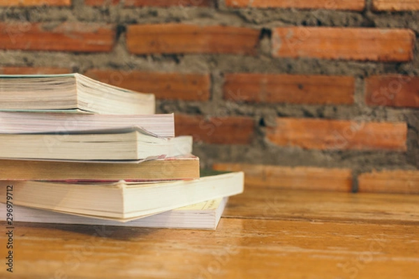Fototapeta Old books on Wooden table in front Brick wall background