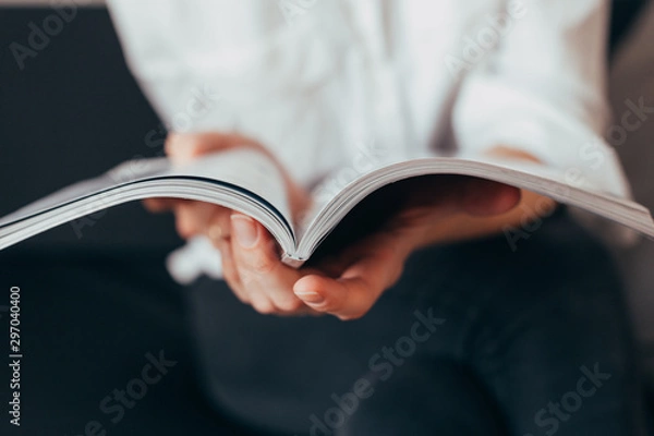 Obraz Beautiful female hands hold an open book or magazine in the room