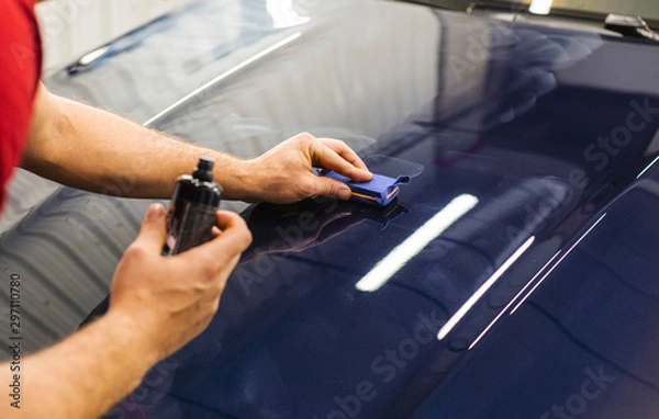 Obraz Car Detailing - A man is applying a nanoprotective coating to a car. A professional ceramic stacker applies different layers to the machine with an applicator sponge. Concept from: Auto Detailing