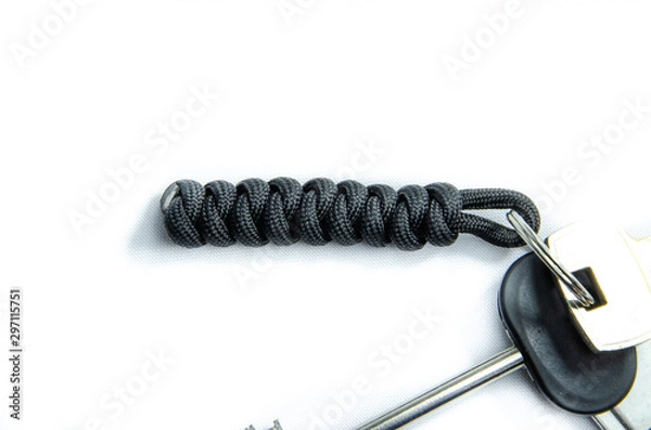 Fototapeta Paracord, weaving rope rope, trinkets lanyards knots. Paracord for tourism and survival. Lanyard on keys and a flash drive on a white background