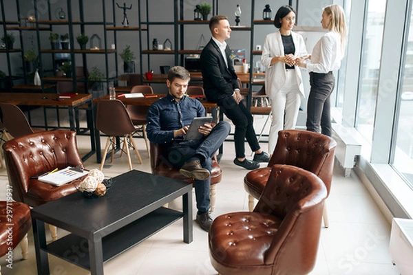 Fototapeta successful young businessman consulting clients online, while his partners brainstorming in the background of the photo. free time, spare time