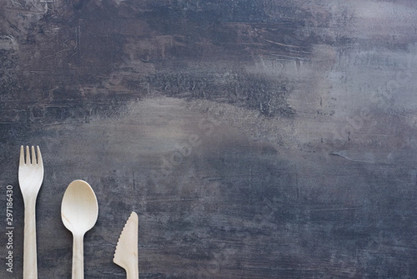 Obraz Top view of natural cutlery - wooden knife, spoon and fork with copy space. Marble black kitchen counter.