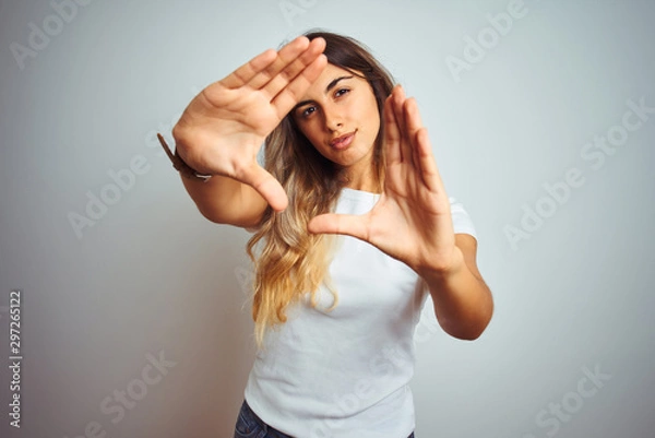 Obraz Young beautiful woman wearing casual white t-shirt over isolated background doing frame using hands palms and fingers, camera perspective
