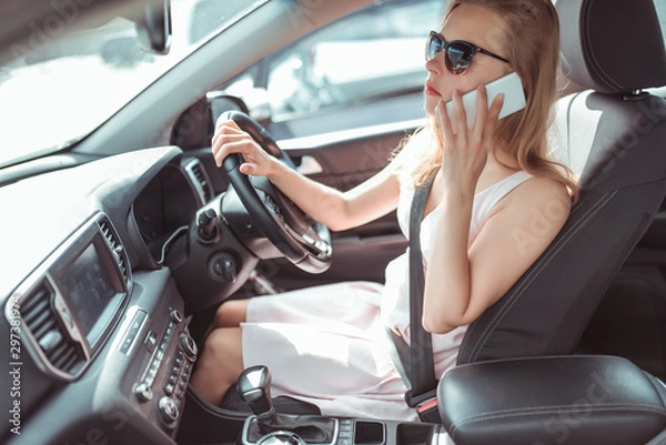 Obraz Girl driving car in cabin. Right-hand drive, left-hand drive. Calls phone, stands in traffic, parking waiting for passenger, specify meeting place. Listens to message in application online call.