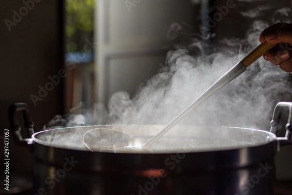 Fototapeta Cooking person in the restaurant is cooking while using the dipper in a large pot. And the water is boiling.