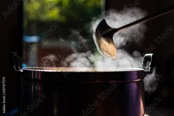 Fototapeta Cooking person in the restaurant is cooking while using the dipper in a large pot. And the water is boiling.