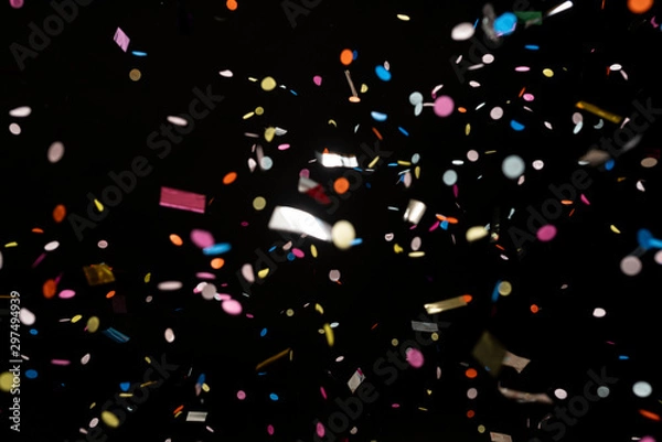 Fototapeta colorful party confetti flying in front of black